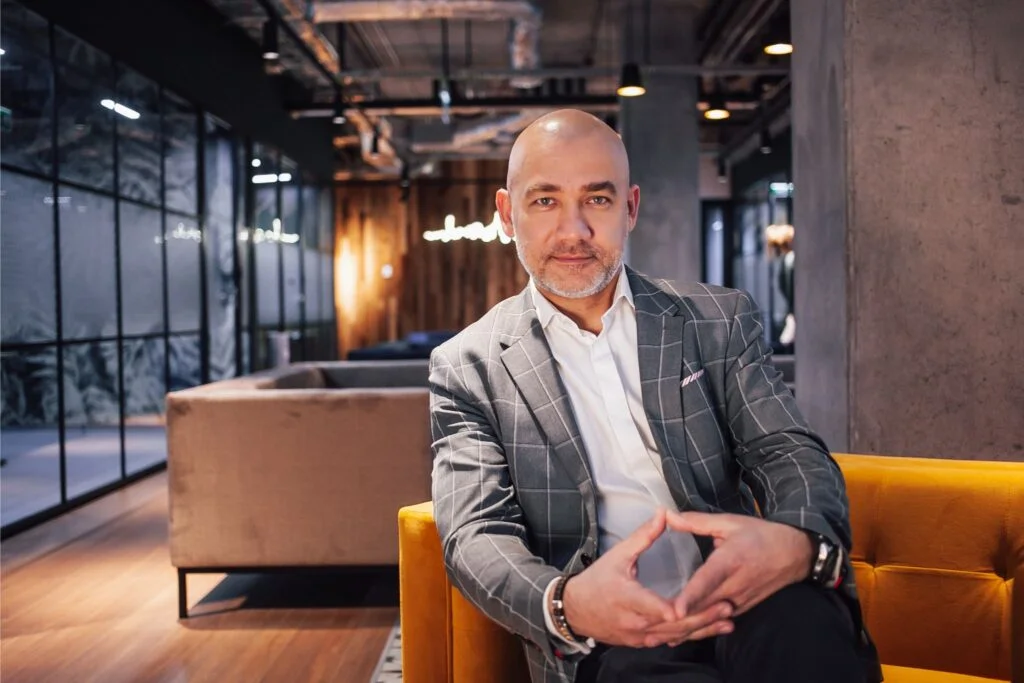 Wiktor ubrany elegancko, siedzący na fotelu i patrzący przed siebie