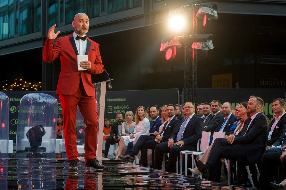 Wiktor Doktór stojący na scenie, gestykuluje i opowiada o czymś, a przed nim wsłuchana publiczność