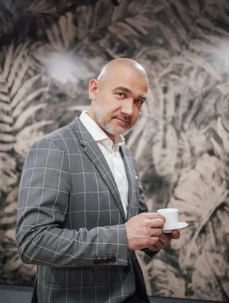 Wiktor ubrany elegancko, siedzący na fotelu i patrzący przed siebie
