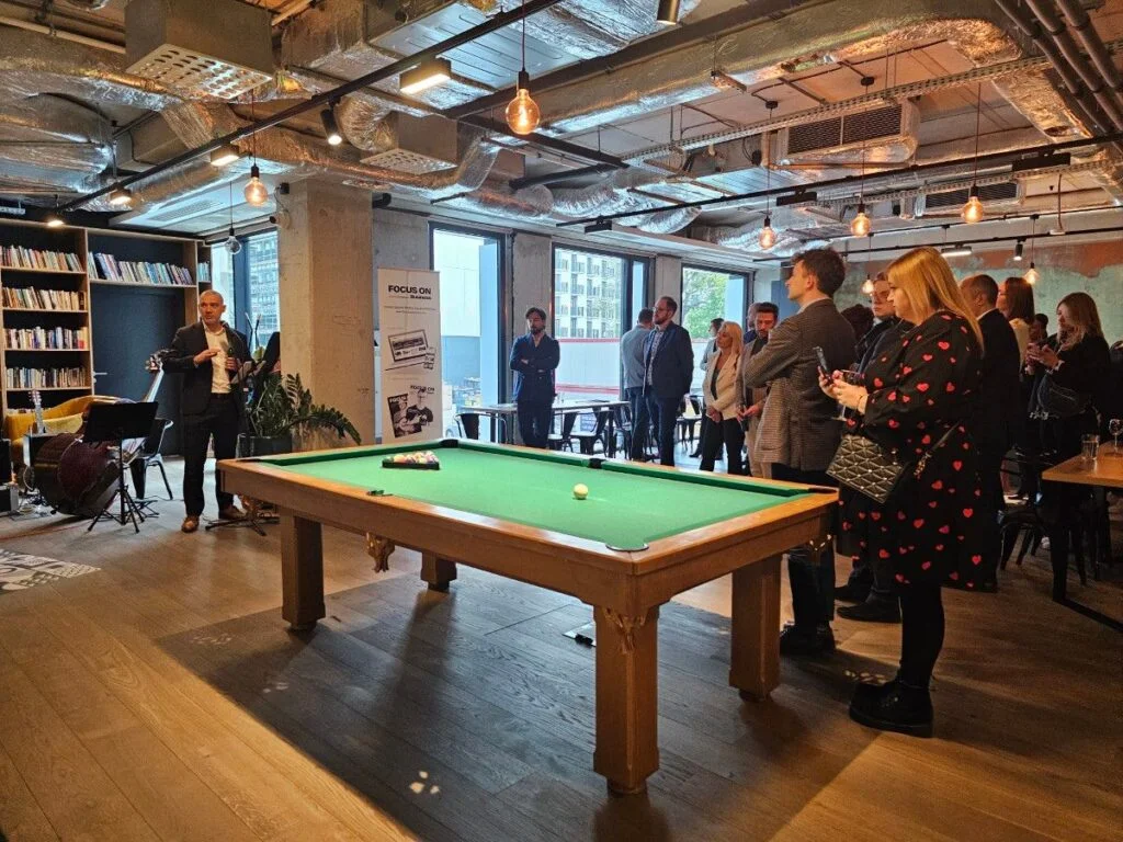 Wiktor Doktór występujący przed patrzącą na niego publicznością, na środku pomieszczenia stoi stół bilardowy